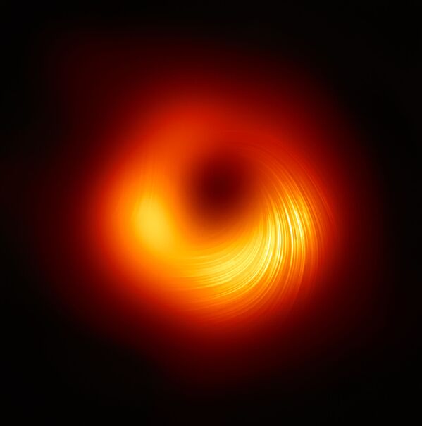 Un agujero negro en la galaxia M87. La imagen, en la que se pueden apreciar los remolinos de los flujos magnéticos, fue publicada el 24 de marzo por los miembros del proyecto científico internacional Event Horizon Telescope. - Sputnik Mundo