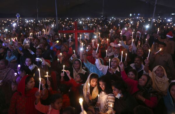 Los cristianos paquistaníes sujetan velas encendidas mientras festejan la Navidad en una plaza de la ciudad de Lahore. - Sputnik Mundo