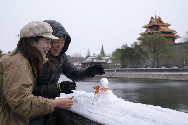 Una pareja construye un muñeco de nieve cerca de la Ciudad Prohibida en Pekín, China, el 7 de noviembre de 2021. - Sputnik Mundo