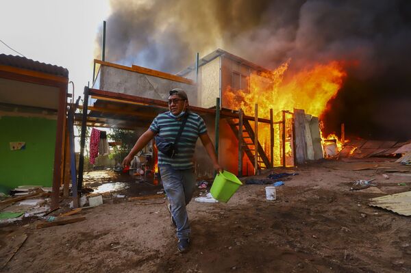 Un hombre ayuda a extinguir el fuego en un edificio vecino en el asentamiento de Laguna Verde. - Sputnik Mundo