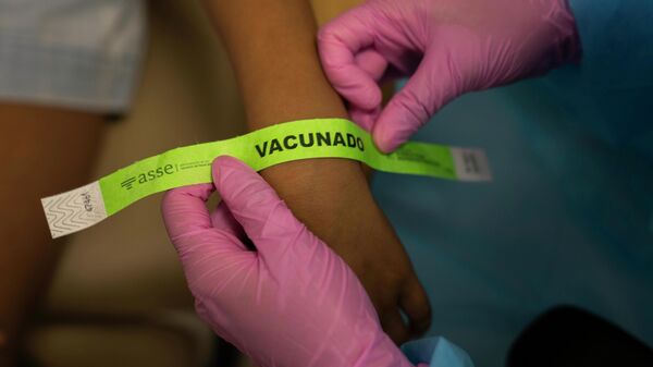Una enfermera asegura un brazalete que dice vacunado - Sputnik Mundo