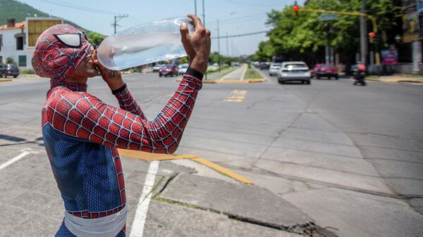 Un hombre disfrazado de Spiderman bebe agua durante la ola de calor en Argentina - Sputnik Mundo