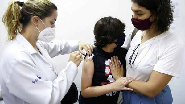 Un niño recibe la dosis de la vacuna anti-COVID-19 de Pfizer en Brasil - Sputnik Mundo