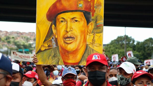 Chavista carga un cuadro de Hugo Chávez en Caracas  - Sputnik Mundo