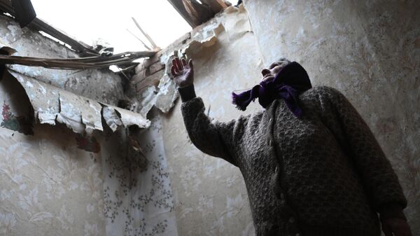 Una anciana muestra el agujero que dejó el impacto de un proyectil en el techo de su casa en la ciudad de Górlovka (República Popular de Donetsk), el 24 de febrero de 2022. - Sputnik Mundo