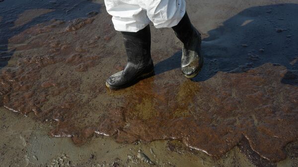 Un trabajador de limpieza camina por la playa de Cavero, contaminada por petróleo, en Ventanilla, Callao, Perú - Sputnik Mundo
