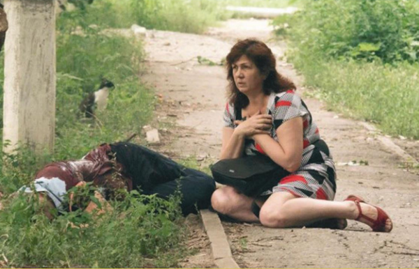 Julio de 2014, Lugansk. Una mujer permanece en estado de shock y se sienta junto a una víctima del bombardeo de las fuerzas ucranianas. - Sputnik Mundo