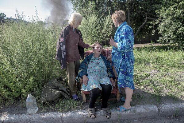 Junio de 2014. Así son las consecuencias de los bombardeos del ejército ucraniano en Slaviansk, región de Donetsk. Los vecinos ayudan a una mujer cuya casa se incendió debido al impacto de un proyectil. - Sputnik Mundo