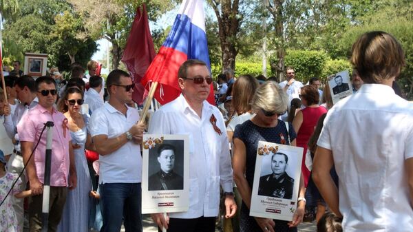 El embajador de Rusia en Cuba, Andrei Guskov (centro) con la foto de su abuelo en el desfile del Regimiento Inmortal desfila en La Habana, Cuba - Sputnik Mundo