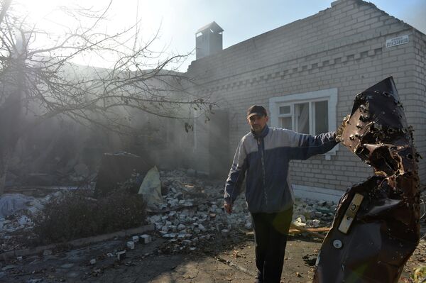 Una puerta metálica sostenida por este residente de Donetsk está literalmente acribillada por proyectiles ucranianos. - Sputnik Mundo