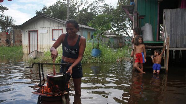 Una residente de Iranduba, estado de Amazonas, Brasil, prepara la comida para su familia en el patio de una casa inundada debido a la crecida del Río Negro.
 - Sputnik Mundo
