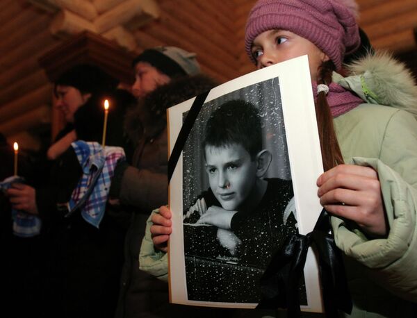 Ucrania ha privado a muchos niños de Donbás no solo de sus padres, sino también de sus amigos cercanos. En la foto: durante un servicio conmemorativo, una niña sostiene el retrato de su amigo Nikita Rusov que murió en Donetsk por la explosión de un proyectil ucraniano el 27 de noviembre de 2014. - Sputnik Mundo