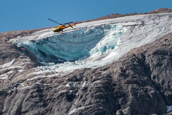 Un helicóptero de rescate sobrevuela el lugar donde se derrumbó una parte de un glaciar en la cordillera de la Marmolada, en los Alpes Dolomitas, Italia. - Sputnik Mundo