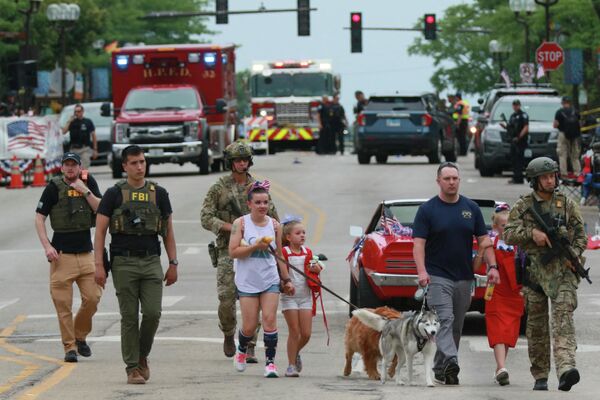 Agentes de la Policía conducen a los lugareños lejos de la escena del tiroteo en el desfile del Día de la Independencia del 4 de julio en el suburbio de Chicago de Highland Park, Illinois, EEUU. - Sputnik Mundo