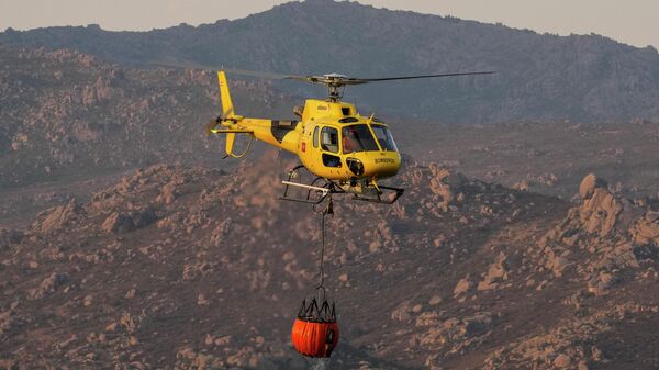 Un helicópterpo con agua durante incendios forestales en España  - Sputnik Mundo