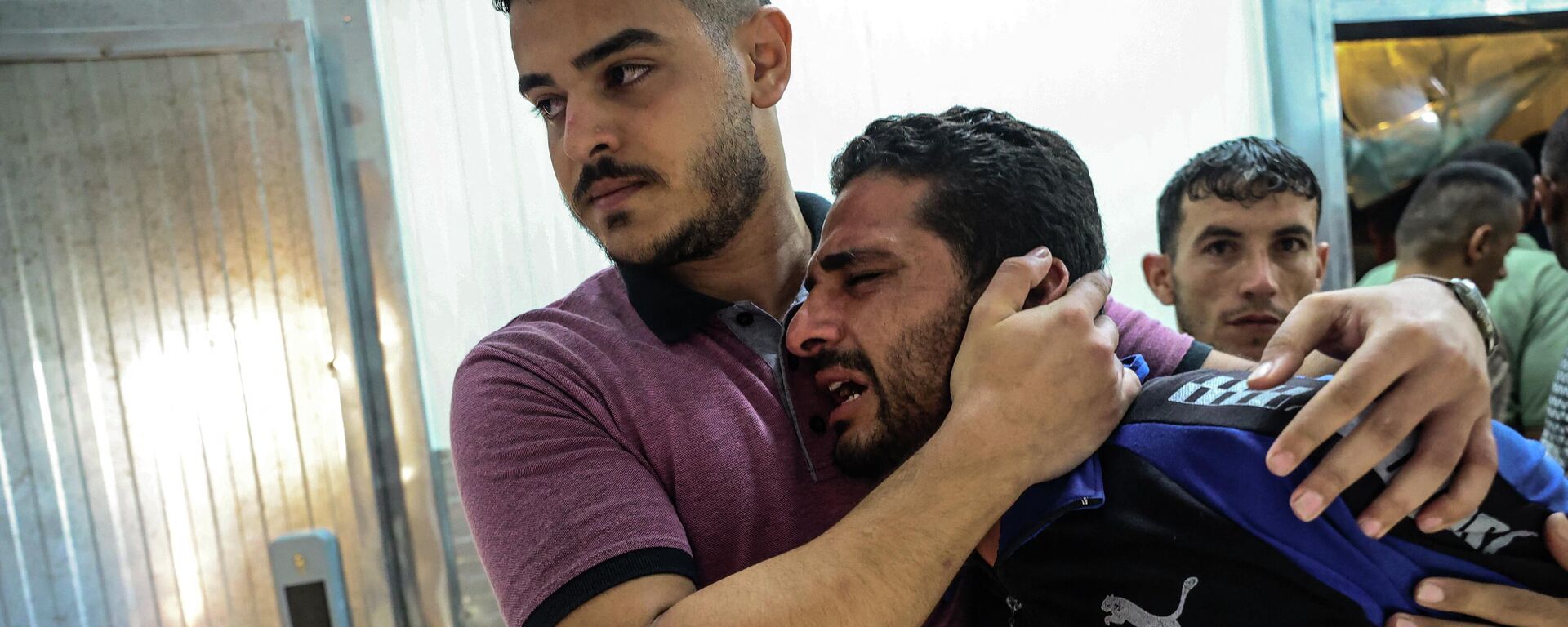 Un hombre palestino reacciona después de identificar el cadáver de pariente en un hospital en el sur de la Franja de Gaza después del ataque aéreo israelí - Sputnik Mundo, 1920, 05.08.2022