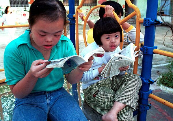 A la derecha Nguyen Thuong Hai, de 8 años, está leyendo un cómic con su amigo en el columpio de la Aldea de Paz de Thanh Xuan en Hanói en 2000. Hai es uno de los 100 niños discapacitados mentalmente y/o físicamente que viven en este centro, que cuida principalmente de las víctimas del Agente Naranja. Los padres del aproximadamente 80% de esto niños sirvieron durante la guerra de Vietnam. - Sputnik Mundo