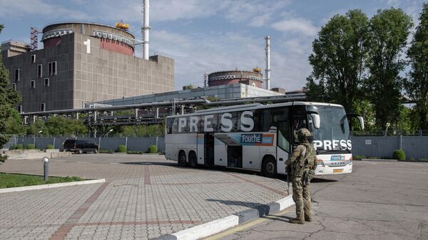 Un soldado ruso y un autobús con prensa internacional en el recinto de la central nuclear de Zaporiyia, en Energodar - Sputnik Mundo