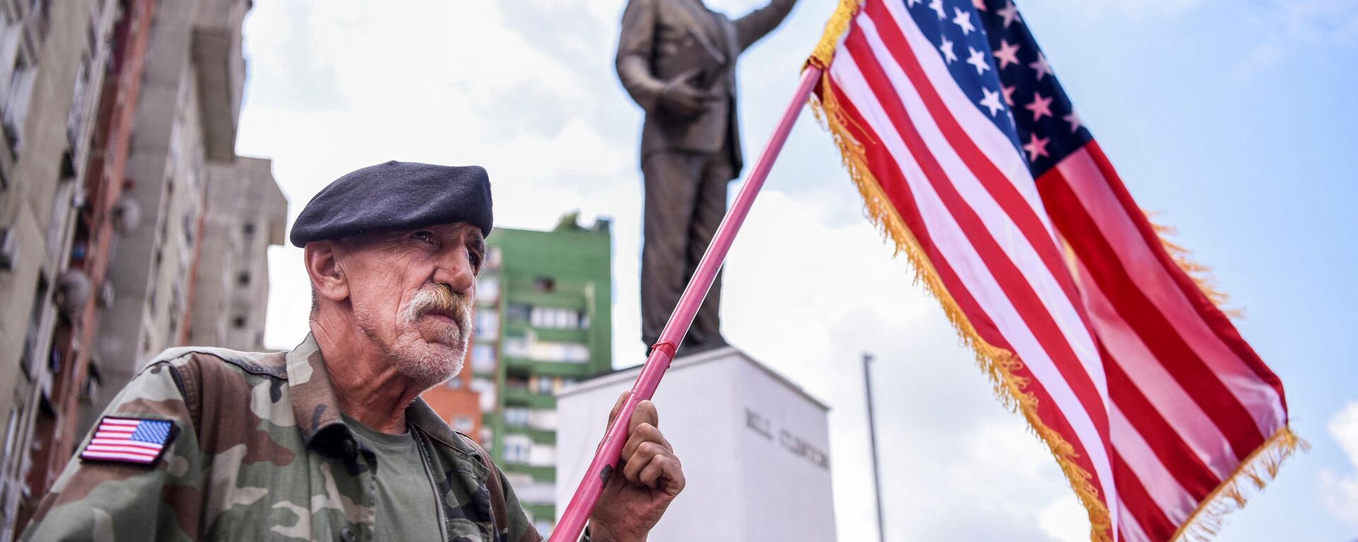Un hombre kosovar de origen albanés sostiene una bandera de EEUU frente a una estatua de Bill Clinton - Sputnik Mundo, 1920, 23.08.2022
