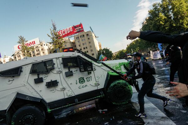 Según la policía, unas 700 personas participaron en los disturbios.En la foto: un participante en los disturbios de Santiago de Chile atacando un coche blindado de la Policía. - Sputnik Mundo