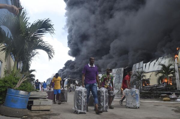 Varios trabajadores retiran las mercancías de una fábrica de Yanuo en llamas en el estado de Ogun, en Nigeria. - Sputnik Mundo