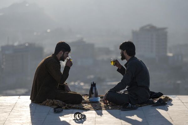 Dos hombres afganos beben té en la cima de la colina de Nadir Khan con la ciudad de Kabul de fondo. - Sputnik Mundo