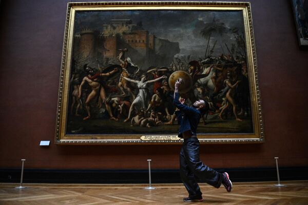 Un hombre baila frente a la obra rapto de las Sabinas de Jacques-Louis David en el Louvre de París, en Francia. - Sputnik Mundo