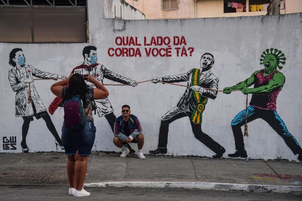 A los artistas de todas las épocas les encanta burlarse de los que están en el poder. No obstante, la caricatura política como género especial de las bellas artes se originó en la Inglaterra del siglo XVIII. Al principio, las caricaturas se publicaban en periódicos y revistas. Hoy en día, las caricaturas ocupan un lugar cada vez más prominente en el arte callejero.En la foto: grafiti del presidente saliente brasileño Jair Bolsonaro compitiendo en un tira y afloja con los médicos durante la pandemia de COVID-19. A los artistas de todas las épocas les encanta burlarse de los que están en el poder. No obstante, la caricatura política como género especial de las bellas artes se originó en la Inglaterra del siglo XVIII. Al principio, las caricaturas se publicaban en periódicos y revistas. Hoy en día, las caricaturas ocupan un lugar cada vez más prominente en el arte callejero.En la foto: grafiti del presidente saliente brasileño Jair Bolsonaro compitiendo en un tira y afloja con los médicos durante la pandemia de COVID-19. - Sputnik Mundo