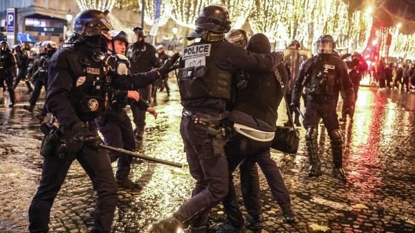 Agentes de la policía francesa se enfrentan a un individuo en los Campos Elíseos mientras los aficionados al fútbol se reúnen tras la derrota de Francia en el último partido de fútbol del Mundial de Catar 2022 entre Argentina y Francia.  - Sputnik Mundo