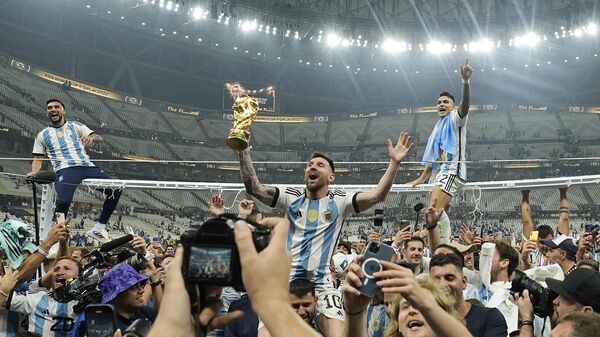 El argentino Lionel Messi celebra con el trofeo ante los aficionados tras ganar la final del Mundial de fútbol entre Argentina y Francia, 18 de diciembre de 2022.  - Sputnik Mundo
