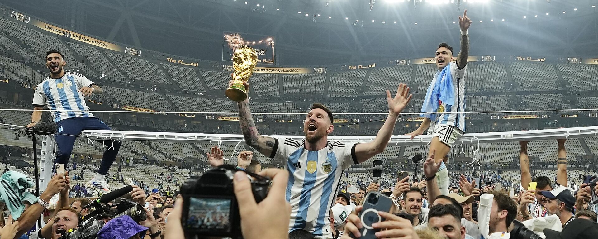 El argentino Lionel Messi celebra con el trofeo ante los aficionados tras ganar la final del Mundial de fútbol entre Argentina y Francia, 18 de diciembre de 2022.  - Sputnik Mundo, 1920, 20.12.2022