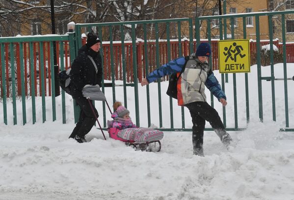 Un hombre y sus hijos juegan sobre la nieve en las zonas residenciales de Moscú. - Sputnik Mundo