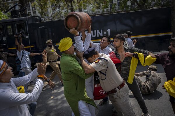 Un policía de Nueva Delhi, la India, trata de detener el 23 de marzo a un simpatizante del legislativo opositor durante una protesta contra la inflación en aumento y el disparo del precio de algunos productos esenciales. En la protesta, el ciudadano levantó un cilindro vacío de gas licuado de petróleo.  - Sputnik Mundo