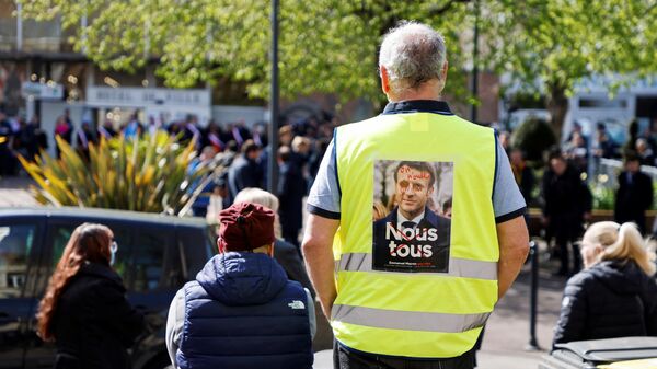 Manifestante del movimiento de los chalecos amarillos con una imagen contra el presidente de Francia, Emmanuel Macron. - Sputnik Mundo