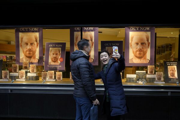 Una pareja hace una foto ante el escaparate de una librería que exhibe el escandaloso nuevo libro del príncipe Harry Spare (En la sombra) en el que habla de las relaciones en la familia real británica. Una pareja hace una foto ante el escaparate de una librería que exhibe el escandaloso nuevo libro del príncipe Harry Spare (En la sombra) en el que habla de las relaciones en la familia real británica. - Sputnik Mundo