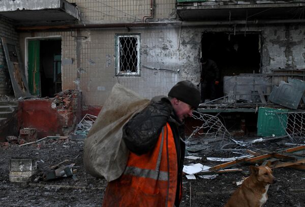 Un hombre retira escombros y restos del patio de una casa destruida por un bombardeo nocturno en Górlovka, república popular de Donetsk, Rusia. - Sputnik Mundo