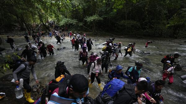 Migrantes cruzan un río durante su camino a través del Tapón del Darién desde Colombia a Panamá. - Sputnik Mundo