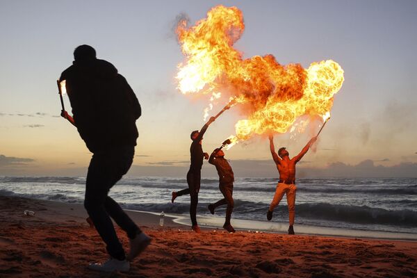 Jóvenes palestinos hacen una demostración del arte de soplar fuego en una playa de la capital del país, Gaza. - Sputnik Mundo