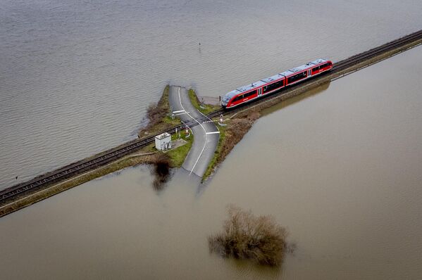 Un tren se aproxima a un cruce en una autopista inundada en Nidderau-Eichen, cerca de la ciudad alemana de Fránkfort. - Sputnik Mundo