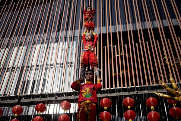 Jóvenes acróbatas forman una torre humana durante una actuación en vísperas del Año Nuevo Lunar en el barrio chino de Bangkok. Jóvenes acróbatas forman una torre humana durante una actuación en vísperas del Año Nuevo Lunar en el barrio chino de Bangkok. - Sputnik Mundo