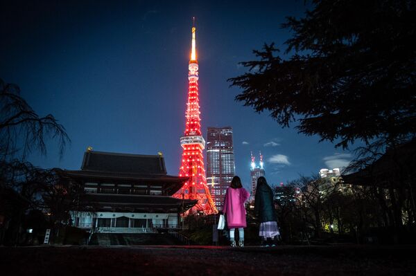 Un grupo de personas visita el templo Zojoji mientras la Torre de Tokio se ilumina de rojo para celebrar el Año Nuevo Lunar chino en Tokio. - Sputnik Mundo