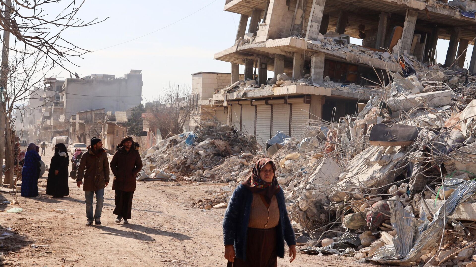 Residentes caminan junto a edificios destruidos, mientras continúan las operaciones de búsqueda y rescate días después de que un mortífero terremoto  en la ciudad de Jindayris, en la parte de la provincia siria de Alepo, el 10 de febrero de 2023.  - Sputnik Mundo, 1920, 01.03.2023