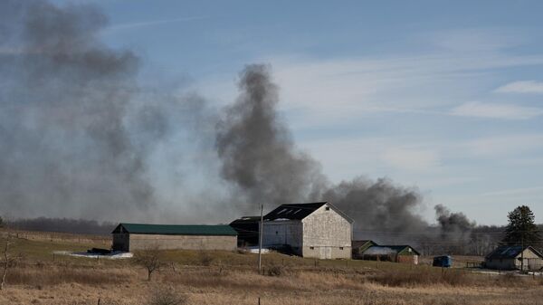 El humo se eleva desde un tren de carga descarrilado en East Palestine, Ohio, EEUU - Sputnik Mundo