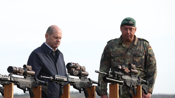 El canciller alemán Olaf Scholz observan los fusiles de asalto HK G36 de las fuerzas armadas alemanas Bundeswehr en Ostenholz, norte de Alemania, el 17 de octubre de 2022. - Sputnik Mundo