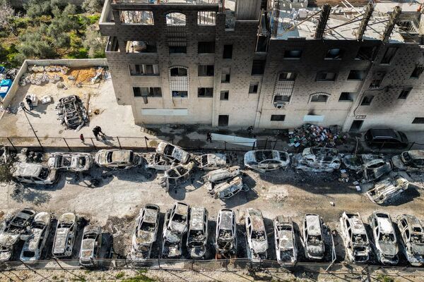Coches palestinos quemados por colonos judíos frente a un edificio calcinado en la localidad de Huwara, cerca de Naplusa, en la Cisjordania ocupada. - Sputnik Mundo