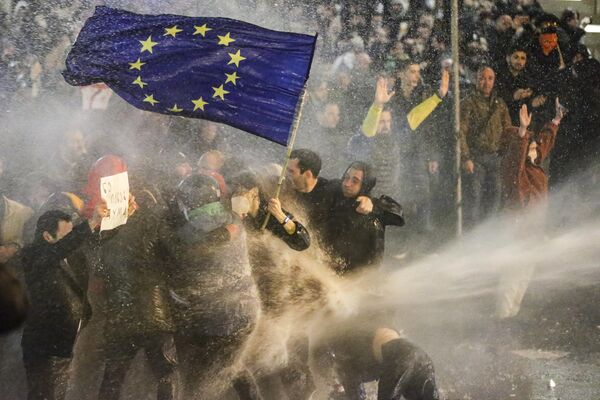 La Policía de Georgia echa agua a los manifestantes que sostienen una bandera de la UE frente al edificio del Parlamento en Tiflis. - Sputnik Mundo