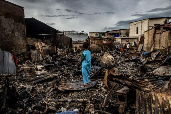 Un niño junto a las cenizas de su casa en el norte de Yakarta, Indonesia. Su hogar se quemó durante un incendio en el depósito de combustible de la empresa estatal Pertamina. - Sputnik Mundo
