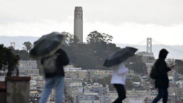 Los peatones llevan paraguas a través de la fuerte lluvia cerca de la calle Lombard en San Francisco, California, el 4 de enero 2023 - Sputnik Mundo
