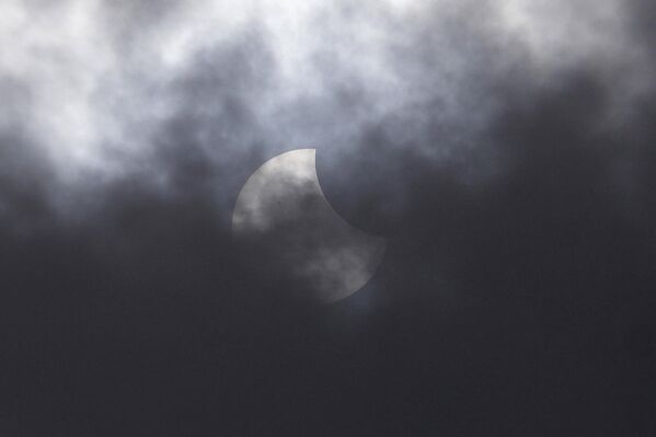 El fenómeno astronómico del 20 de abril abrió un corredor de eclipses que durará hasta el 5 de mayo.En la foto: el eclipse solar parcial se ve a través de la nube sobre Yakarta, Indonesia. - Sputnik Mundo