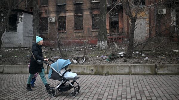 Una mujer con un cochecito de bebé en una calle de Mariúpol - Sputnik Mundo